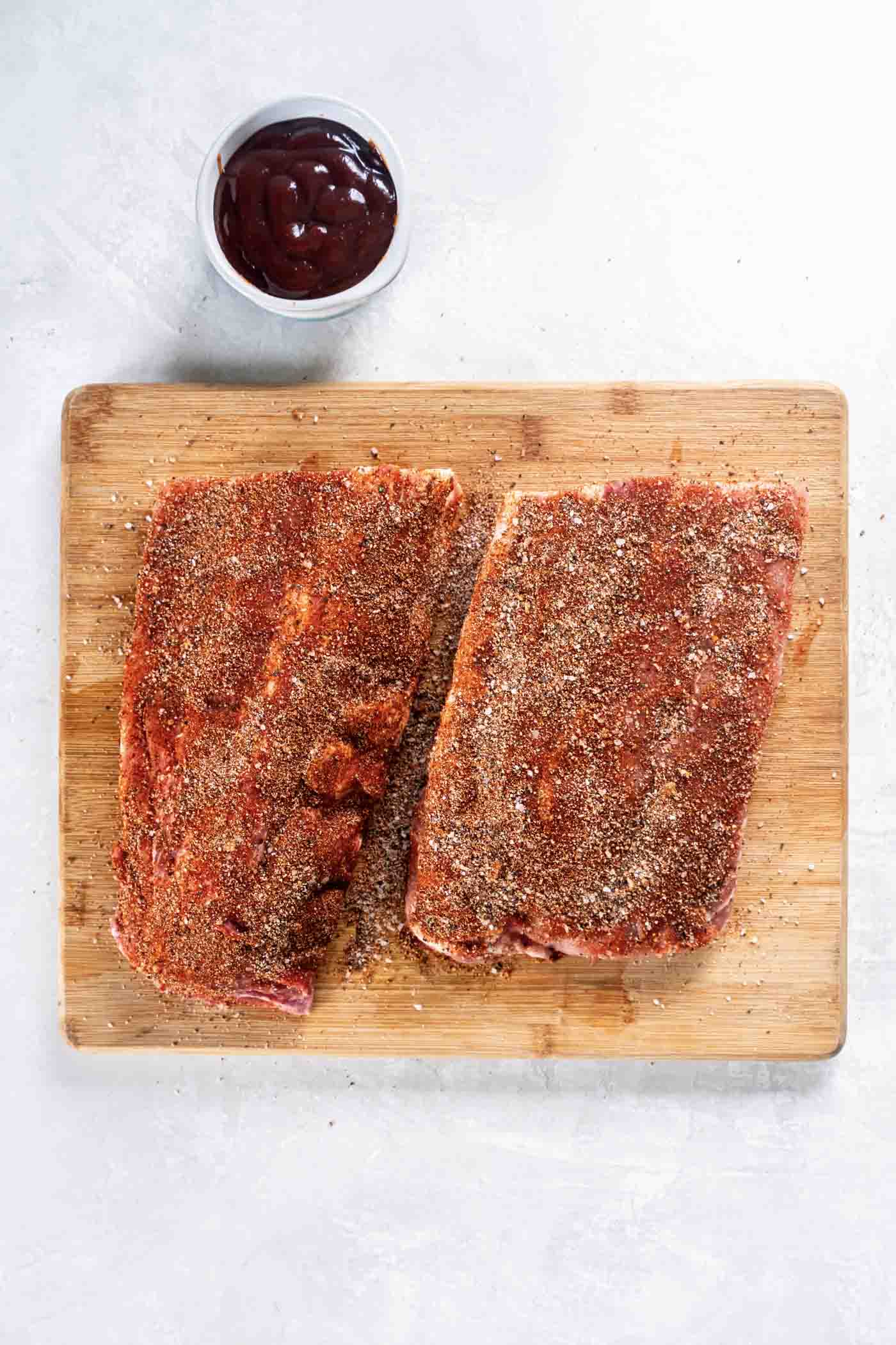 Learn how to make the BEST Instant Pot Ribs! Fall-off-the-bone tender and so easy to make, this recipe includes cook times for baby back pork ribs and spare ribs, plus how to cook ribs from frozen. Spice mixture rubbed on raw baby back ribs on a cutting board.